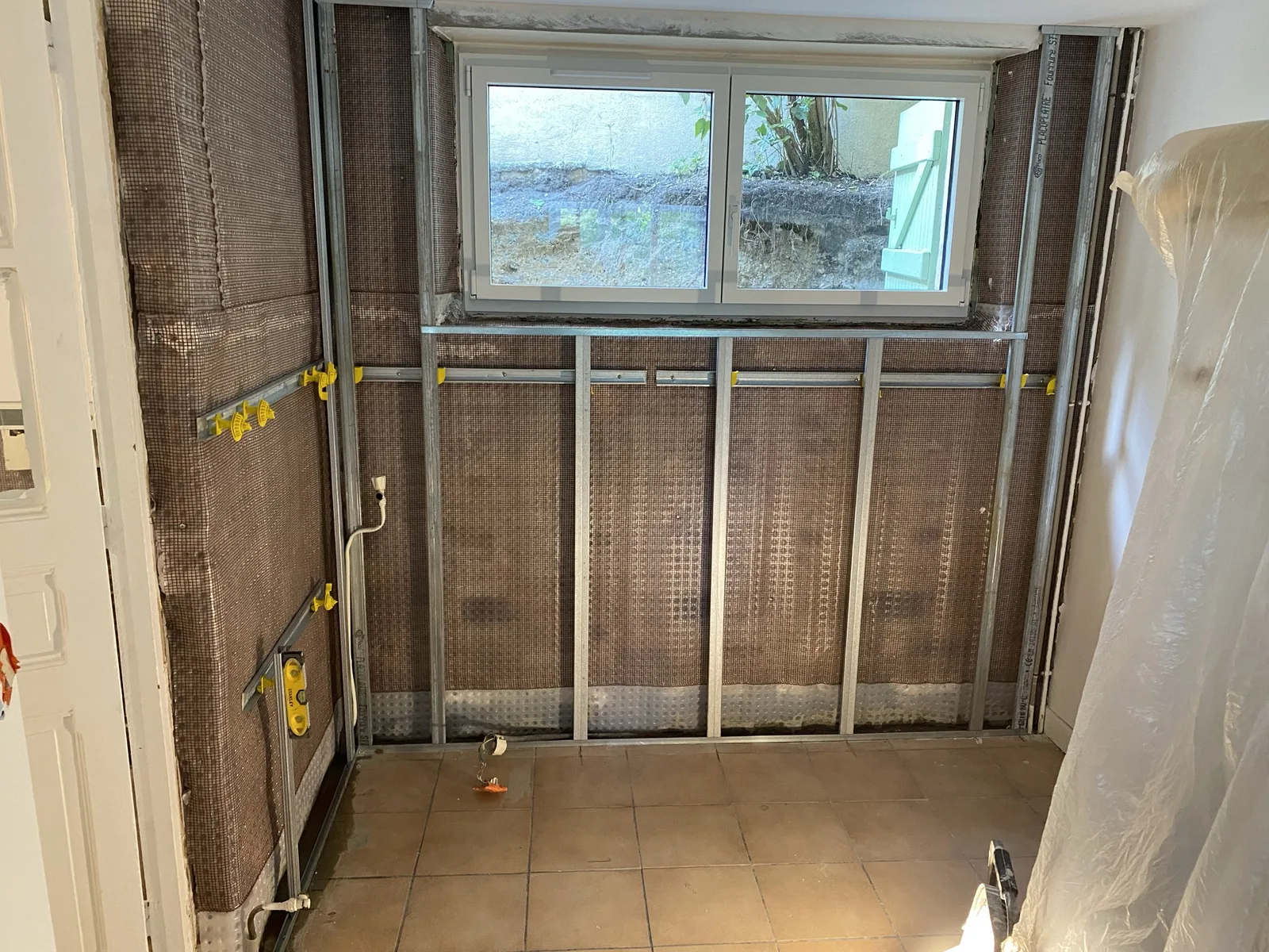 Doublage BA13 hydrofuge en cours sur le mur traité