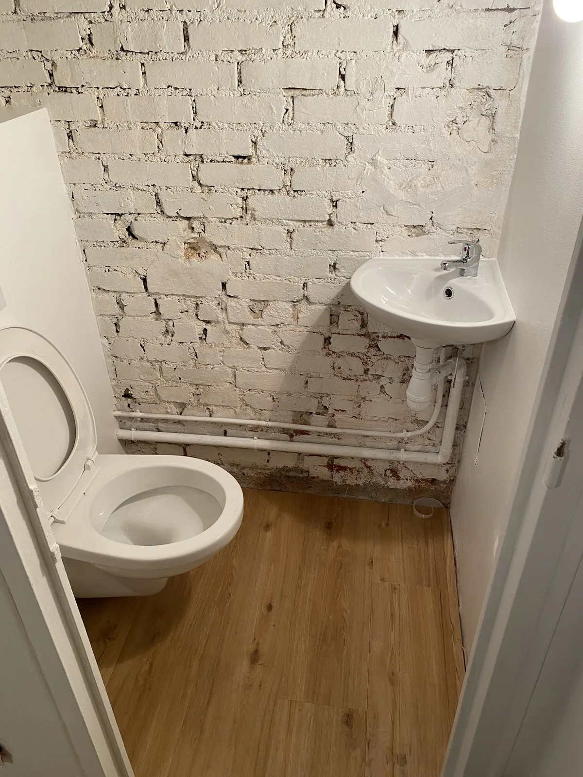 WC suspendu terminé avec lave-mains d'angle, mur en brique peint